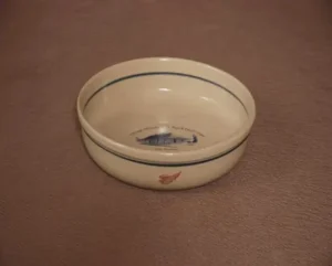 Cream Red Wing pottery bowl with blue rim lines and a Wells depot illustration inside.